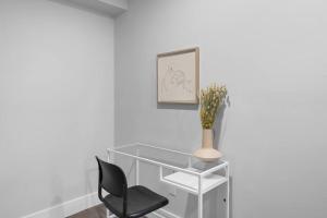 a glass desk with a black chair and a vase at Stylish 1BR Duplex w/Free Parking & Wi-Fi in Dieppe