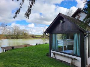 eine kleine Hütte mit einem Tisch am Fenster neben einem Fluss in der Unterkunft Cottage du Diot, son lac et son île in Bannegon