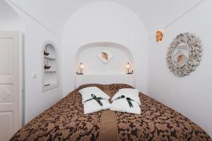 a bedroom with a bed with two pillows on it at Fanari Villas in Oia