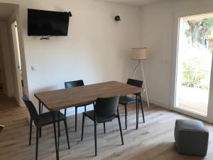 a dining room table with chairs and a television on a wall at Résidence Fiori di Cala Rossa in Lecci