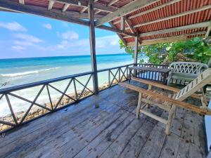 una terraza de madera con un banco en la playa en Paseo Del Mar Seaside Inn, en Jagna