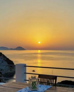 a sunset over the water with a table and a bench at Ponza Le Forna in Ponza