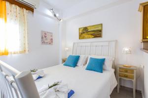 a bedroom with a white bed with blue pillows at Vera's Apartments in Kassiopi
