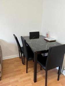 una mesa negra con 4 sillas y un ordenador portátil. en 30% Off Monthly Stay/2bed /Erith en Erith