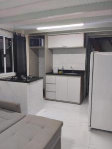 a kitchen with white cabinets and a refrigerator at Cananéia Chalé 23 in Ilha Comprida
