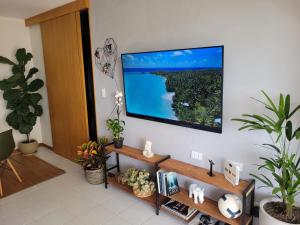 sala de estar con TV de pantalla plana en la pared en Apartamento Boutique Barra da Tijuca Península, en Río de Janeiro