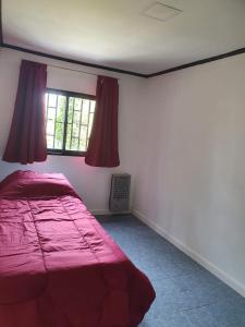 a bedroom with a red bed and a window at Los manzanares, casa histórica in Veintiocho de Noviembre