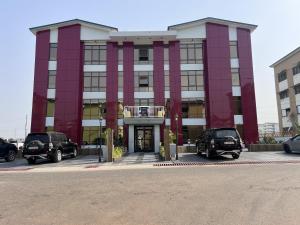 un edificio rojo y blanco con coches estacionados en un estacionamiento en Panafest Two Block - 3Fingers, en Accra