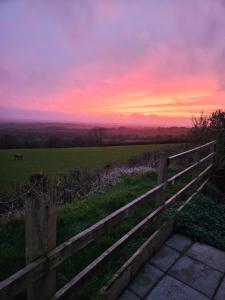 a fence in a field with a sunset in the background at Meadow View in Haverfordwest
