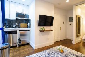 a kitchen with white cabinets and a flat screen tv at 69-3A Prime LES Modern Brand New 1BR in New York