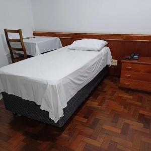 a bedroom with a large bed and a wooden floor at Hotel Firenze in Londrina