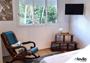 - une chambre avec une chaise, un lit et une fenêtre dans l'établissement Les Hauts de Devarieux - Sérénité & Horizon, à Garnier