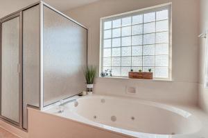 Una bañera blanca en un baño con ventana. en Stockton Home with Deck and Gas Grill about 1 Mi to Lake!, en Stockton 20 fotos más