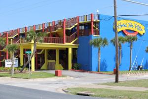a yellow and blue building with palm trees in front at Hotel DeVille in Corpus Christi