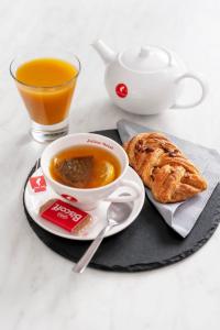 eine Tasse Tee, einen Teller Gebäck und eine Tasse Orangensaft in der Unterkunft Giagi B&B in Trient