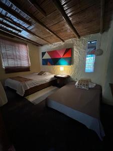 a bedroom with two beds and a painting on the wall at Cabaña Canto de las Aguas Cañón del Combeima in Ibagué