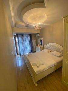 a bedroom with a large white bed with a ceiling at Baku - Park Azure with sea view two bedrooms and one living room in Baku
