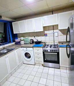 a kitchen with a stove and a washing machine at Anju's sweet Stay in Sharjah