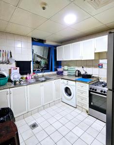 a kitchen with white cabinets and a washing machine at Anju's sweet Stay in Sharjah