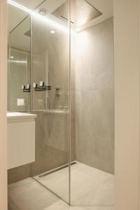 a shower with a glass door next to a sink at Apto Ribeira Lisboa in Lisbon