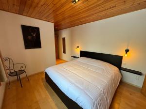 a bedroom with a large bed and a wooden ceiling at La Villa des Vennes in Heure