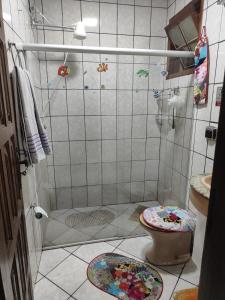 een badkamer met een douche, een toilet en matten bij Suíte independente a 10 minutos da praia in Vila Velha