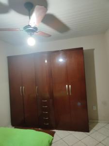 um quarto com uma ventoinha de tecto e armários de madeira em Suíte independente a 10 minutos da praia em Vila Velha