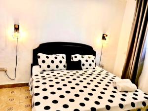 a black and white bed with black polka dot pillows at Retreat Homes in Dar es Salaam