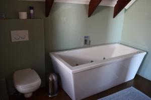 a bathroom with a white tub and a toilet at Hemel op Aarde Villa in Dwarskersbos