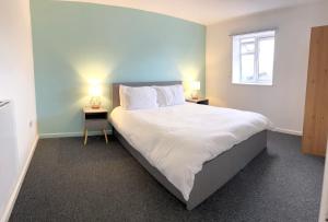 um quarto com uma grande cama branca e 2 candeeiros em Entire Flat in Canary Wharf em Londres