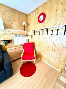 a living room with a red chair and a red clock at Esquí y Relax Apartamento in Sierra Nevada
