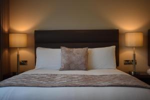 un letto con cuscini bianchi e 2 lampade; di The Birches Killarney a Killarney