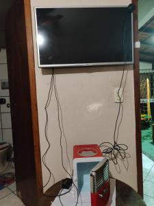 a flat screen tv hanging on a wall with a machine at Suíte independente a 10 minutos da praia in Vila Velha