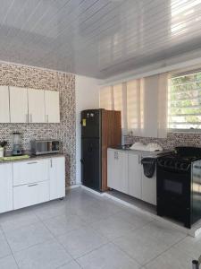 uma cozinha com armários brancos e um frigorífico preto em Hermosa cabaña la Promesa en Malambo. em Malambo