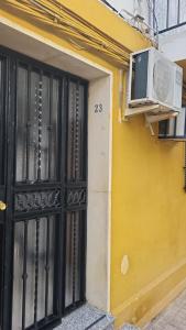Edificio amarillo con ventana y aire acondicionado en Disfruta de un barrio tranquilo, en Alcalá de Guadaira