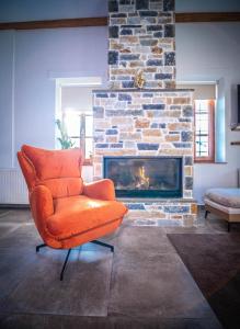 an orange chair in a living room with a fireplace at SELO Luxury Suite in Álli Meriá