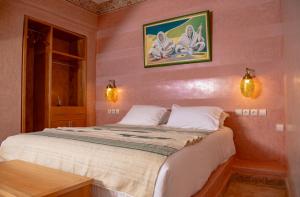 una camera da letto con un grande letto e pareti rosa di Palais Riad Hida a Oulad Barrehil