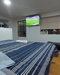 1 dormitorio con 1 cama y TV en la pared en CASAROMERO, en Huancayo