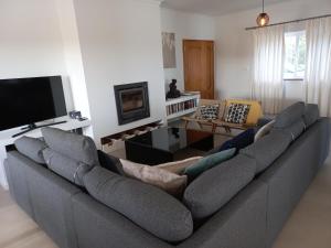 a living room with a large couch and a tv at Casa Tin Tin in Moncarapacho