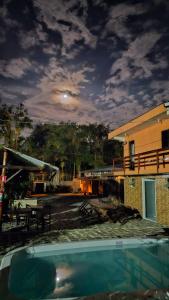 a pool in front of a building with the moon in the sky at Pousada Dona Carmem Ubatuba in Ubatuba
