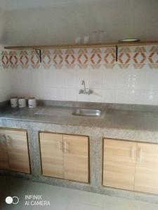 uma cozinha com um lavatório e armários de madeira em Residence Delaure em Bingerville
