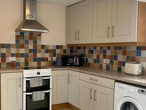 a kitchen with white cabinets and a microwave at Harbour Views 3 Bed Townhouse with private off street parking and office in Portstewart +8 photos