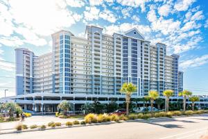 a large building with palm trees in front of a street at Lighthouse in Gulf Shores
