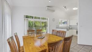 cocina y comedor con mesa de madera y sillas en Tranquil At Hibbard - 21 Hibbard Drive, en Port Macquarie