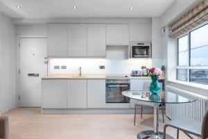 a kitchen with white cabinets and a glass table at Nell Gwynn House Apartments & Rooms in London