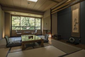 a living room with a table and a large window at Takamiya Bettei Kuon in Tsuruoka