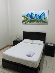 1 dormitorio con 1 cama y una pintura de mariposas en Residencial Brest Amazon Tarapoto, en Tarapoto
