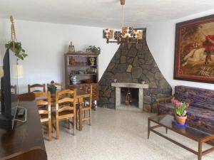 a living room with a stone fireplace and a dining room at El Escondite del Tiétar in Lanzahita
