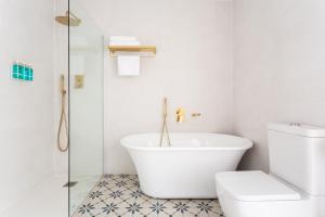 a white bathroom with a tub and a toilet at Divino Hotel Boutique in Sitges