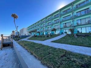 a building on the beach with a pathway next to it at Makai Beach Lodge in Ormond Beach